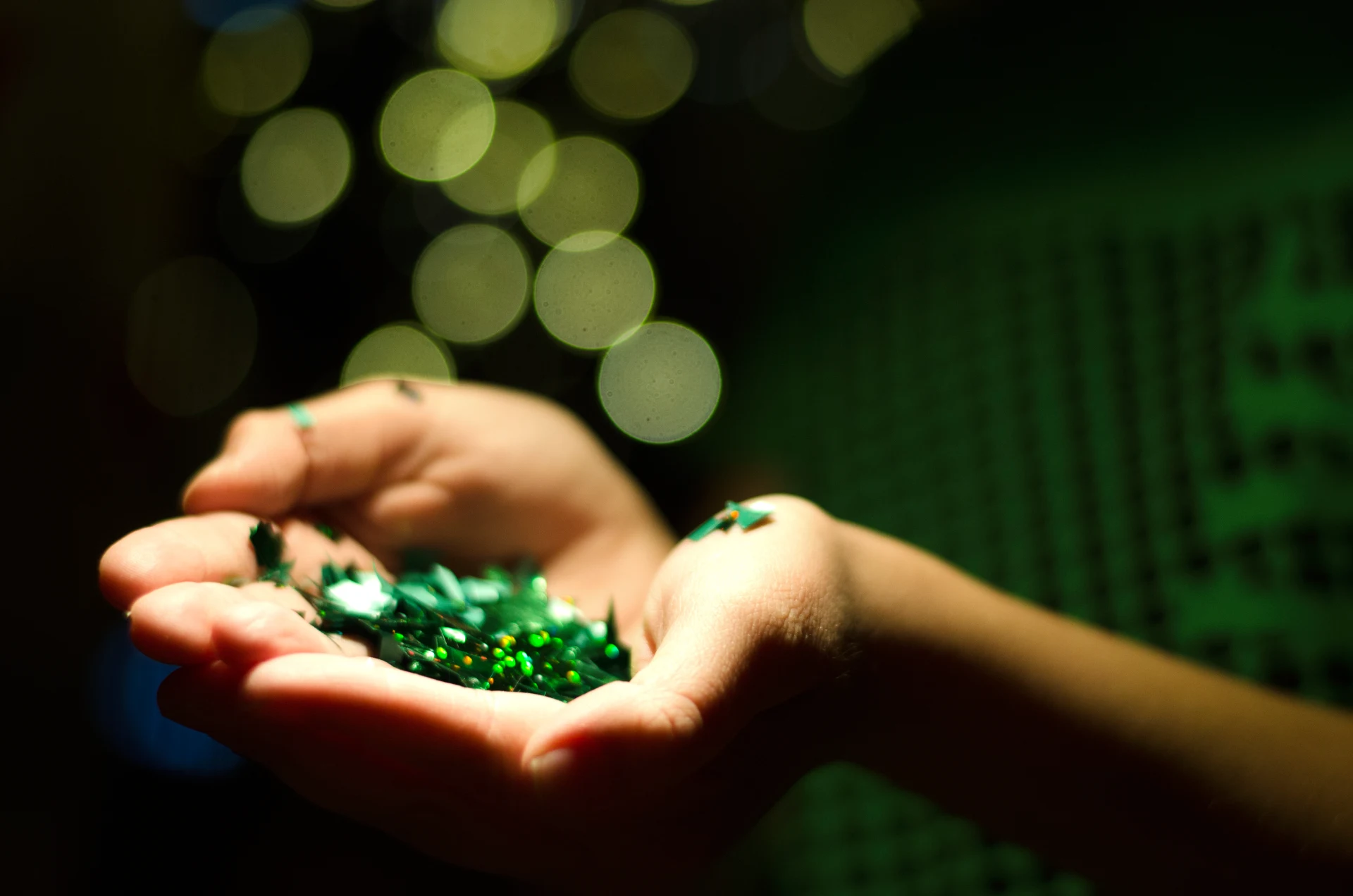Green confetti falling into open hands.
